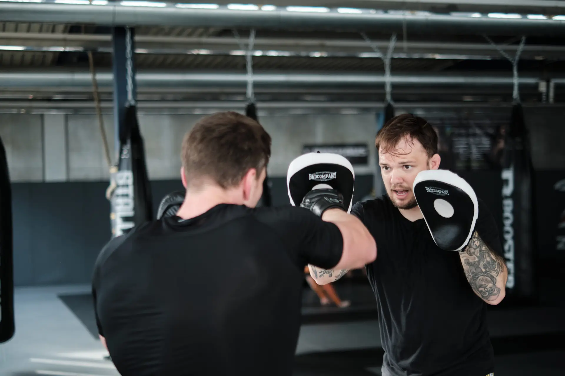 Hauzel Kampfsport Stuttgart Ludwigsburg Degerloch Möglingen MMA Krav Maga Gym Fitness Zentrum Selbstverteidigung Sporttraining Kampfperformance Kampfschule. Training für Erwachsene und Kinder – Sportlicher Mann trainiert mit Trainer im Gym und schlägt zu.