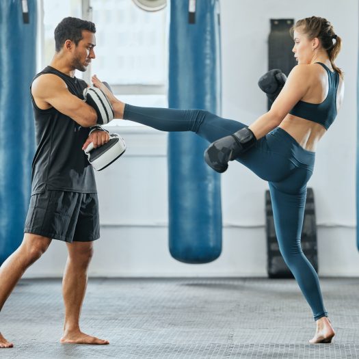 Hauzel Kampfsport Stuttgart Ludwigsburg Degerloch Möglingen MMA Krav Maga Gym Fitness Zentrum Selbstverteidigung Sporttraining Kampfperformance Kampfschule. Training für Erwachsene und Kinder – Frau mit Boxhandschuhen beim Schlagtraining.
